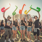 Teenagers at an outdoor music festival holding inflatable saxophones in the air