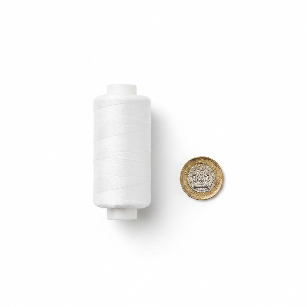 White cotton sewing thread reel beside a UK £1 coin on white background showing product size — 500 yards cotton thread