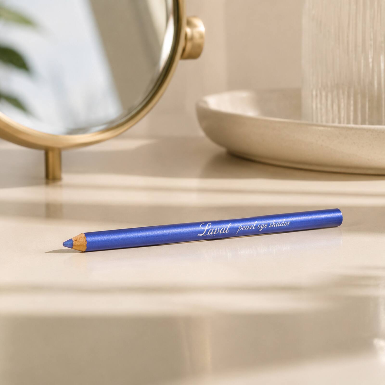 Laval Sapphire Blue eyeshadow pencil displayed on a neutral dressing table beside a mirror