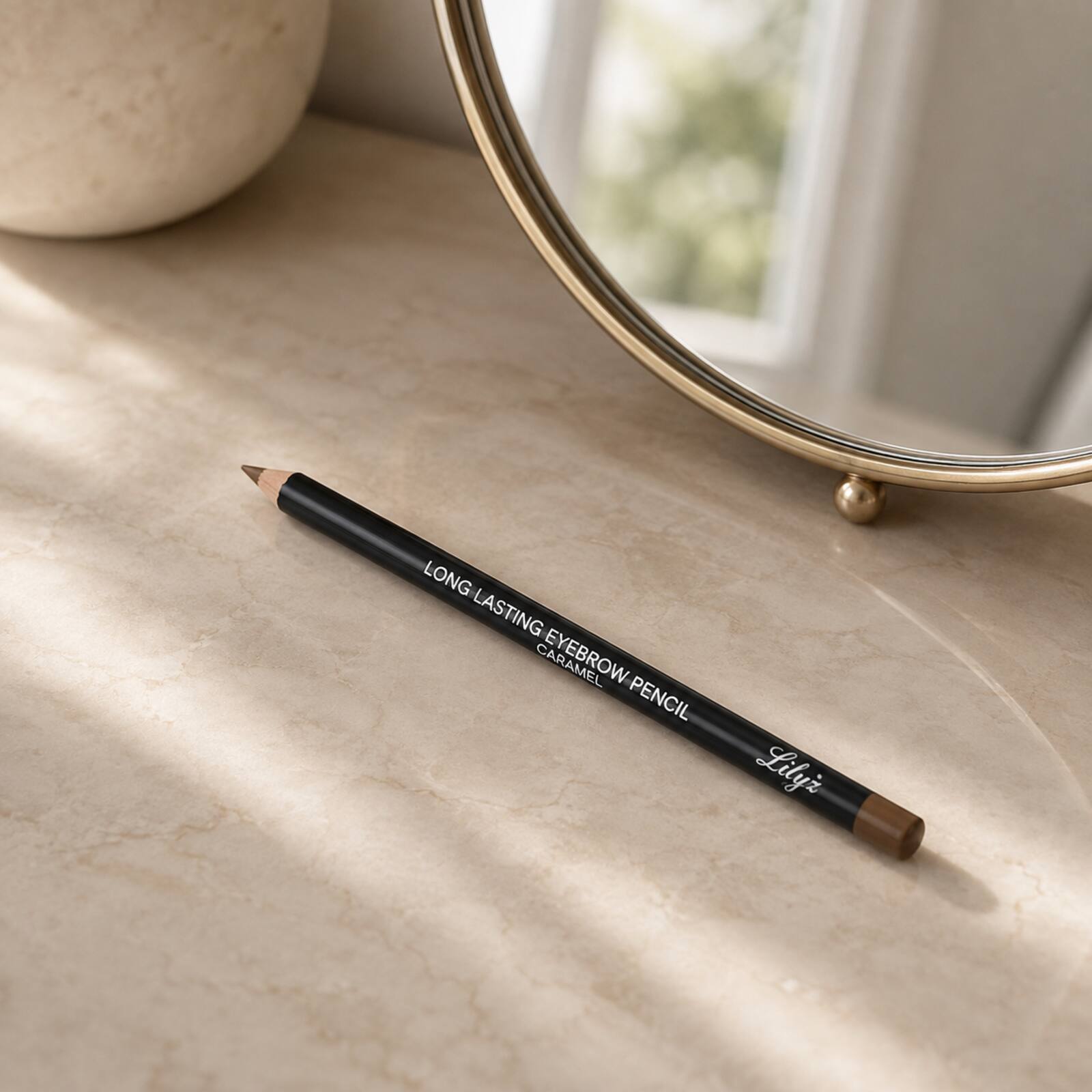 Lilyz Caramel Brown eyebrow pencil displayed on a neutral dressing table beside a mirror