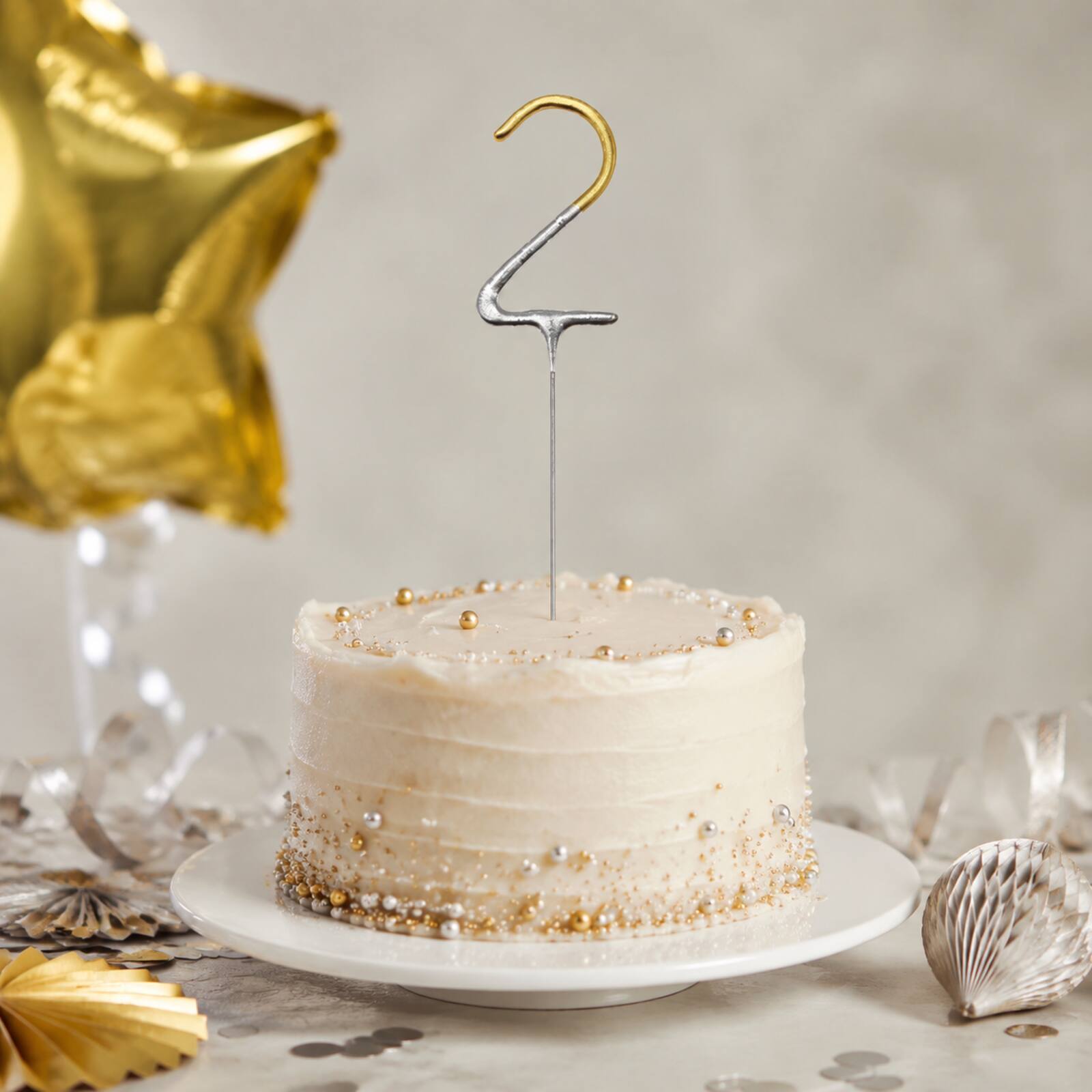 Unlit gold number 2 birthday sparkler in a silver and gold party display