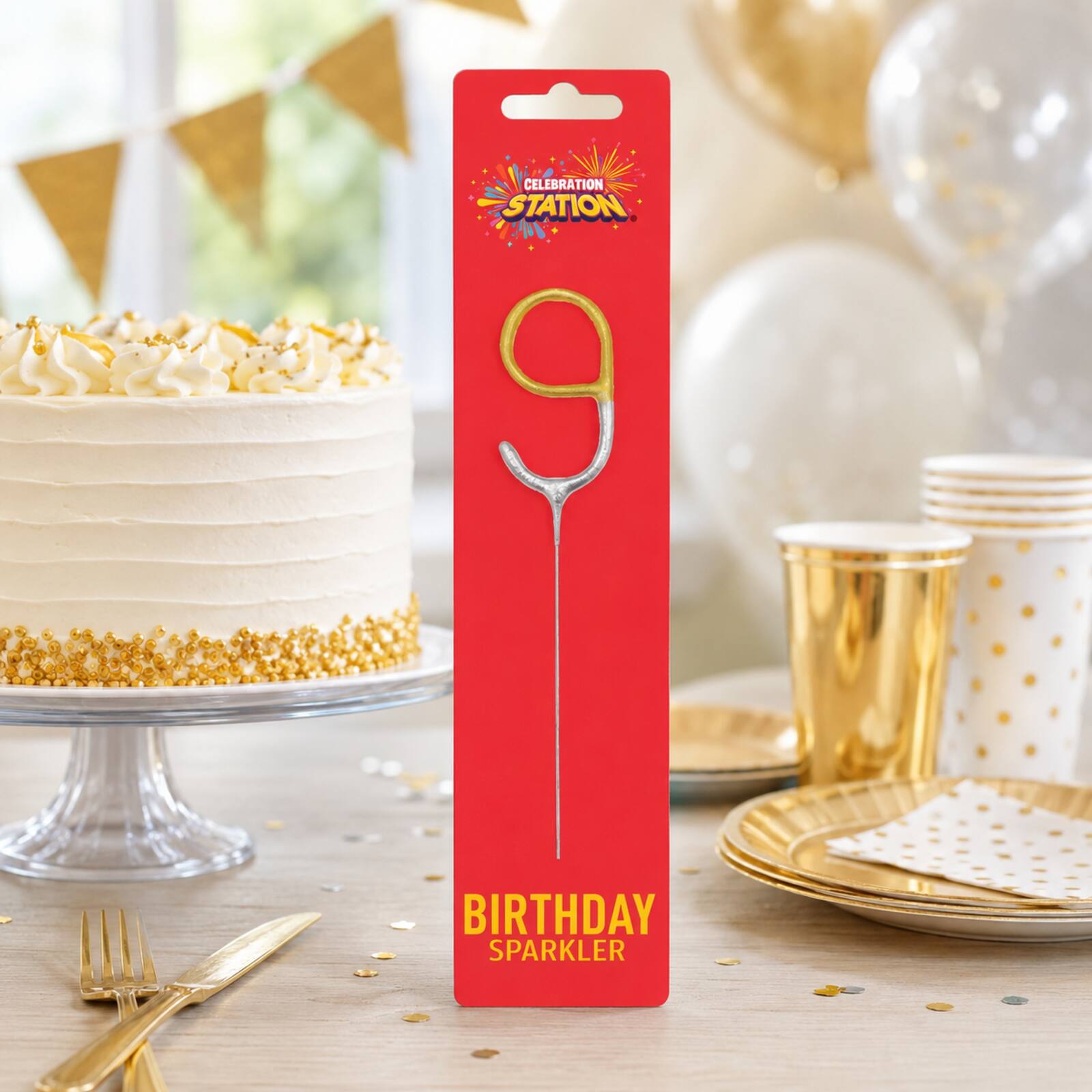 Packaged number 9 gold and silver birthday sparkler beside a birthday cake and tableware