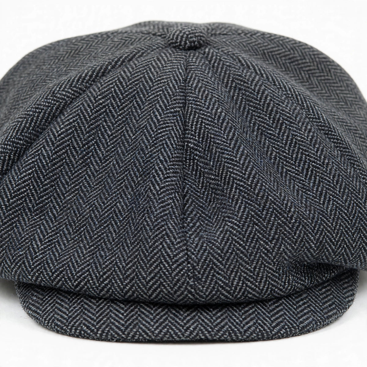 Close-up view of grey herringbone Peaky Blinders style flat cap with structured peak