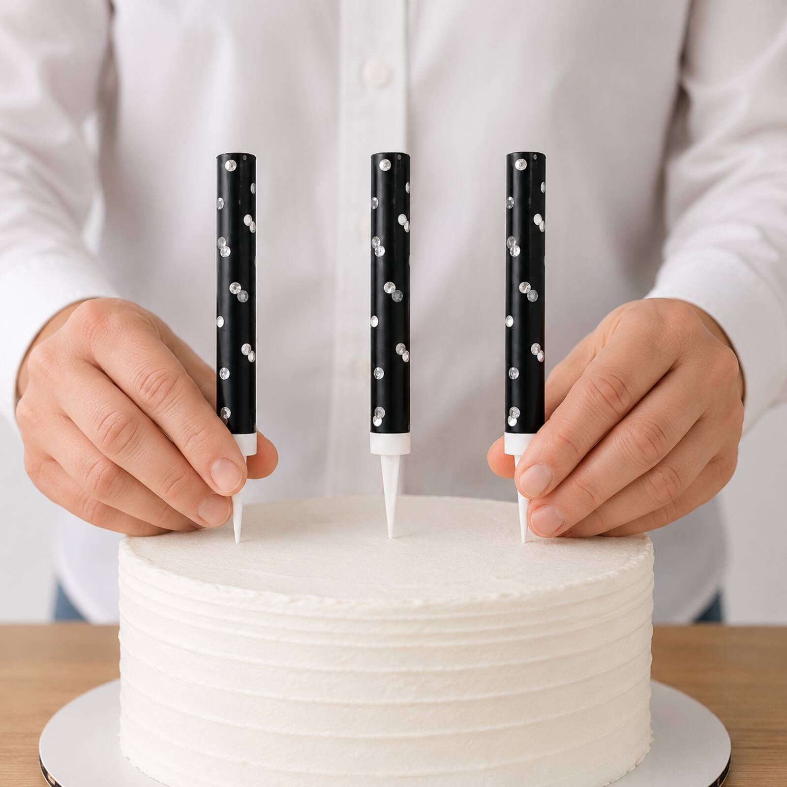 Adult safely placing three unlit black cake fountains into a cake