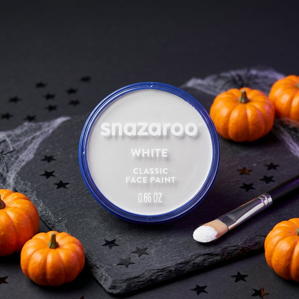 A round jar of Snazaroo Classic Face Paint in White, surrounded by small orange pumpkins, a makeup brush, and a dark slate background with star-shaped cutouts.