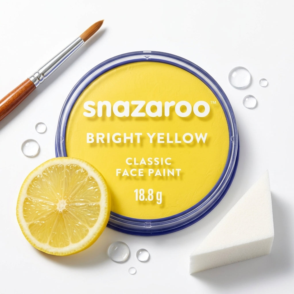 Snazaroo Bright Yellow Classic Face Paint in a round tin with a blue rim, styled on a white background with a lemon slice, a paintbrush, and a sponge.