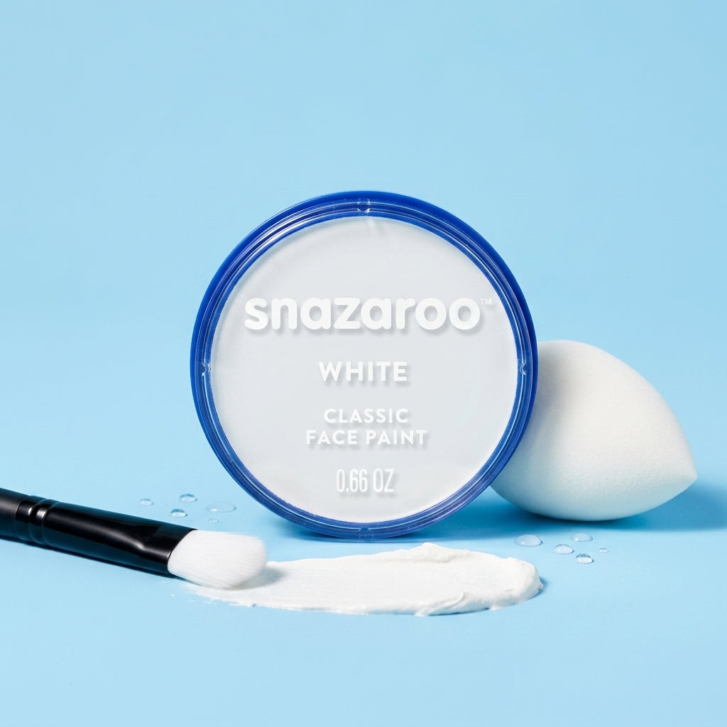 A round tin of Snazaroo Classic Face Paint in the shade White, shown open with white cream paint spilled in front, a white makeup sponge, and a makeup brush on a light blue background.