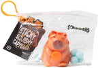 Scrunchems Sticky Squishy Capybara in retail packaging — clear zip bag with black branding label and orange hanger