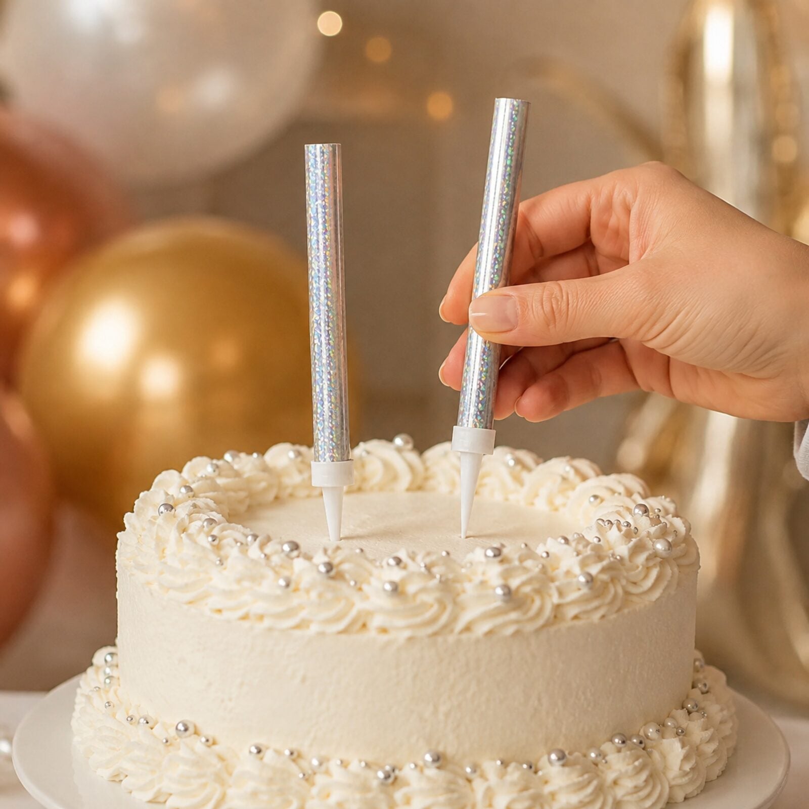 Adult placing two silver prismatic ice fountain decorations into a birthday cake