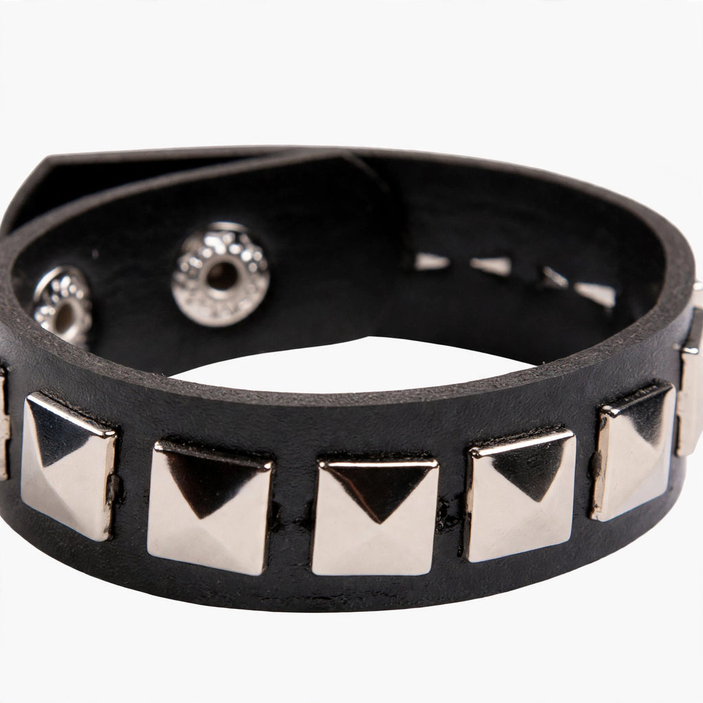 Close-up view of black leather wristband with silver pyramid studs