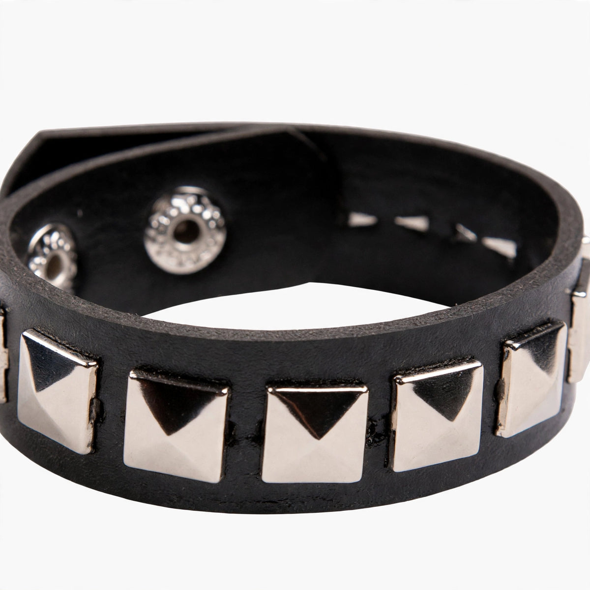 Close-up view of black leather wristband with silver pyramid studs