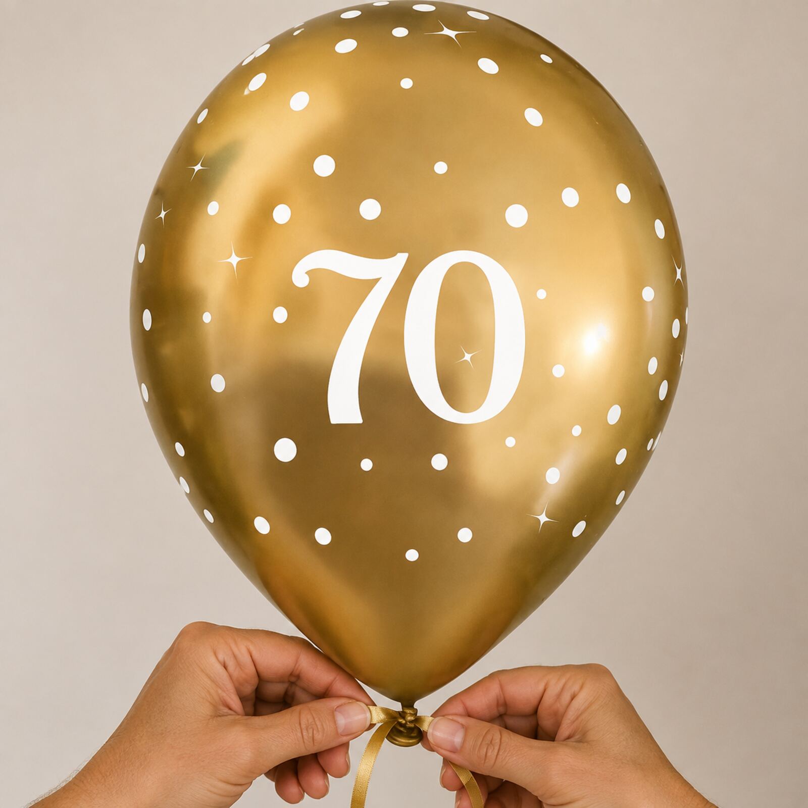 Adult hands safely tying a gold number 70 birthday balloon